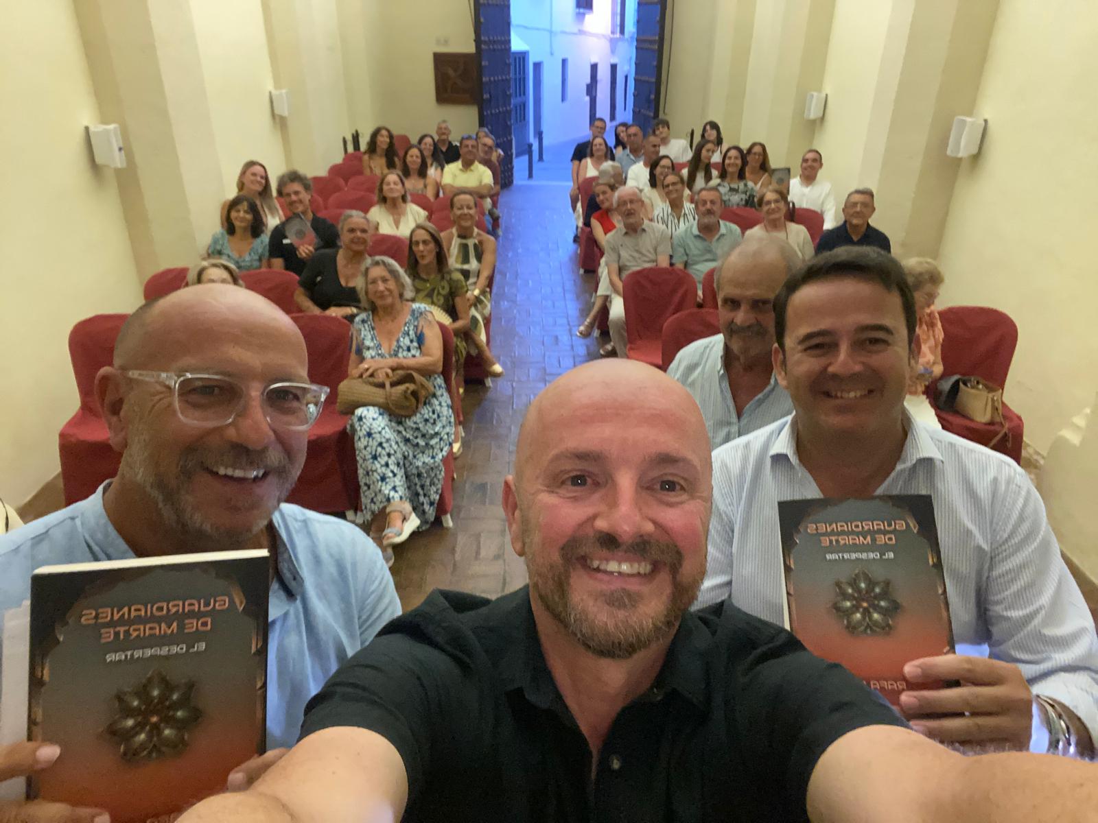 Rafa Gil junto a Rafael Carmona Priego y Andrés Camarena Muñoz, con el público asistente a la presentación de El Despertar en la Capilla de la Misericordia de Arcos de la Frontera.